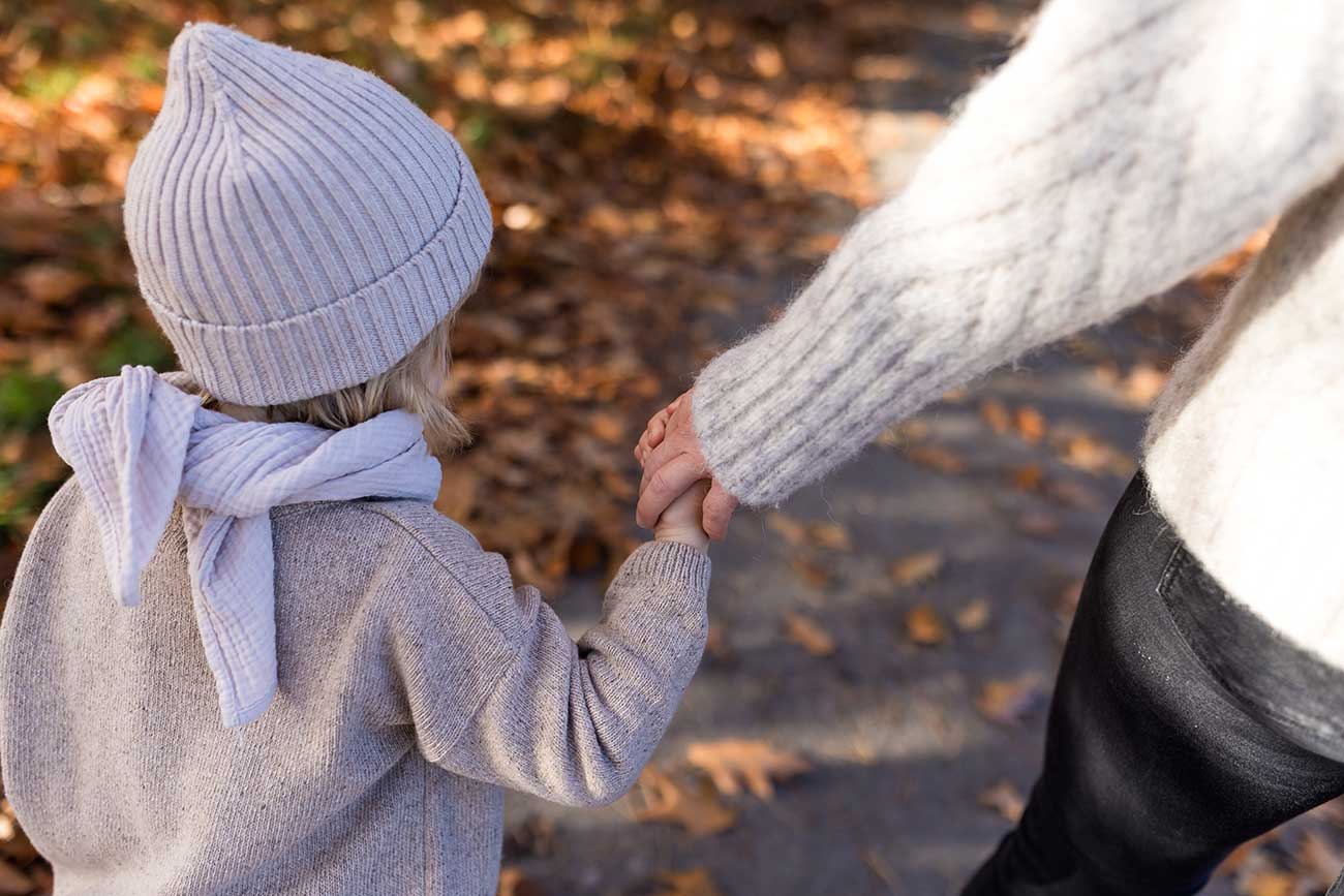 Kind mit Strickmütze und Schal in Naturtönen beim Familienshooting